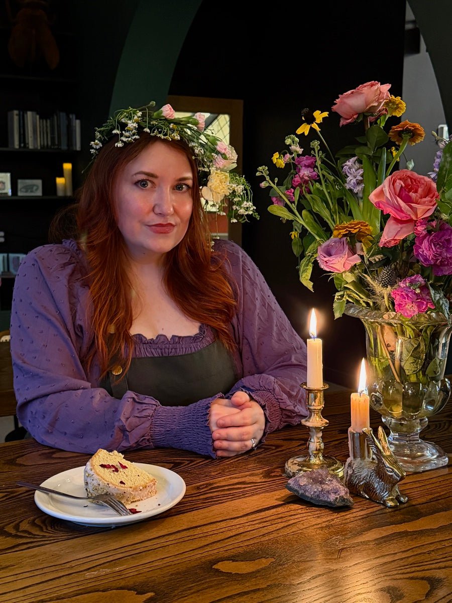 Deanna Holdcraft in a flower crown, seated at a candlelit table at Witches Brew Coffee Co.