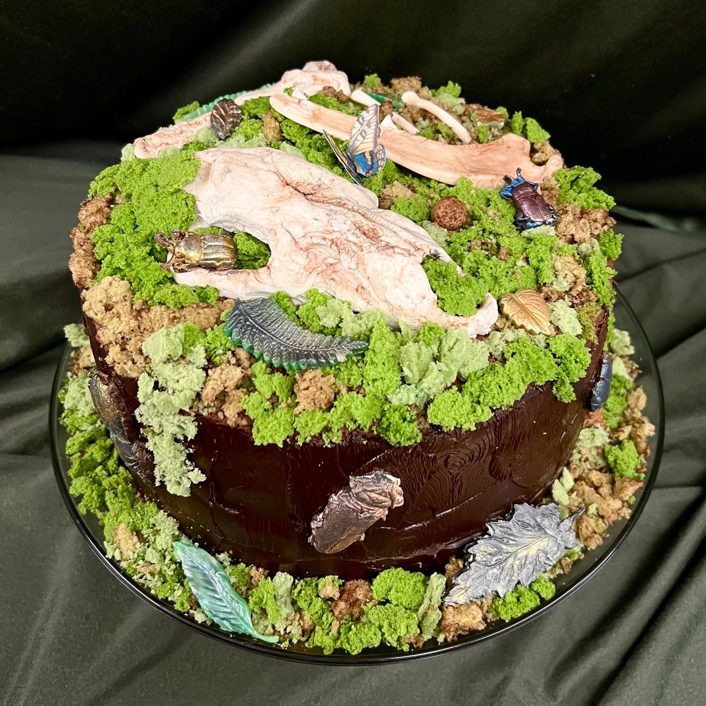 The forest floor cake: chocolate cake dressed as woodland ground with moss, leaves, bones, and beetles